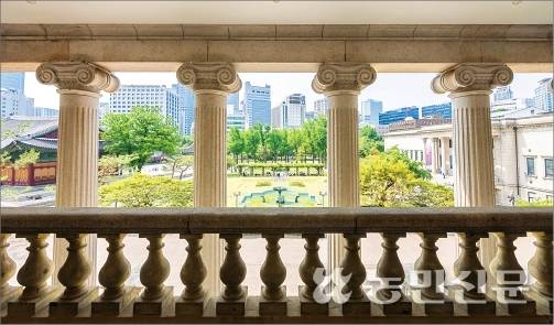 나선형 머리 장식이 있는 이오니아식 기둥 사이로 유럽풍 정원과 한옥 전각, 주변의 빌딩들이 한눈에 보인다.