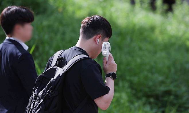여름 기운이 돌기 시작하는 절기 '소만'인 지난 21일 서울 종로구 일대에서 반팔을 입은 시민이 손선풍기를 사용하며 출근하고 있다. 뉴스1