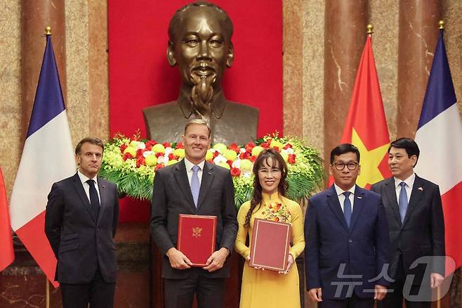 에마뉘엘 마크롱 프랑스 대통령(좌), 르엉 끄엉 베트남 주석(우), 바우터 반 베르쉬 에어버스 국제 총괄 부사장(좌 두번째), 베트남 항공사인 비엣젯의 딘 비엣 푸엉 최고경영자(우 두번째), 응웬 티 푸엉 타오 회장(중앙)이 26일 하노이 대통령궁에서 협약서를 교환하며 포즈를 취하고 있다. ⓒ AFP=뉴스1 ⓒ News1 신기림 기자