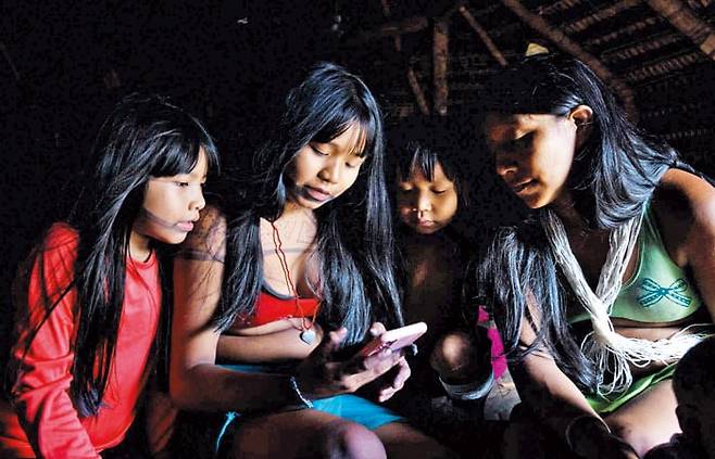 2023년 9월 인터넷 서비스 ‘스타링크’가 설치된 아마존 마루보족 어린이들이 스마트폰을 들여다보는 모습. /뉴욕타임스