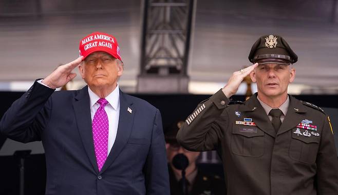 붉은 모자와 진홍색 넥타이를 착용한 도널드 트럼프 미국 대통령(왼쪽)이 24일(현지 시간) 뉴욕주 웨스트포인트의 육군사관학교 졸업식에 참석해 경례하고 있다. 
웨스트포인트=AP 뉴시스