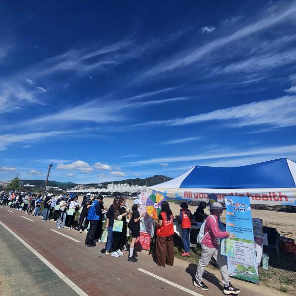 탈춤축제 기간 동안 낙동강 힐링로드 걷기대회가 열리고 있다. 참여자들이 안동시보건소 건강 체험부스 앞에서 줄을 서고 있다.