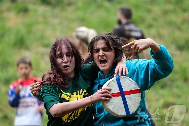 26일(현지시간) 영국 브록웍스의 쿠퍼스 힐에서 열린 '구르는 치즈 잡기' 대회에서 참가자들이 치즈 바퀴를 들고 포즈를 취하고 있다. ⓒ 로이터=뉴스1