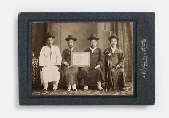 1910년 황성기독교청년회 학교 사진과 1회 졸업생인 민충식이 1906년 4월, 해외로 떠나기 전 친구들과 기념사진을 찍는 모습. 촬영 날짜와 이유, 등장인물이 적힌 액자를 들고 찍었다. 국립민속박물관