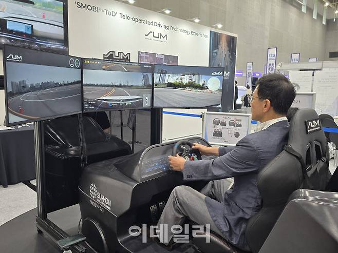 ‘2025 수원 ITS 아태총회’ 참가자가 에스유엠의 원격주행 시스템 ‘SMOBI-ToD’를 체험하고 있다. 이곳에서 차량을 운전하면 서울대 시흥캠퍼스에 있는 차량을 원격 조종할 수 있다. (사진=황영민 기자)