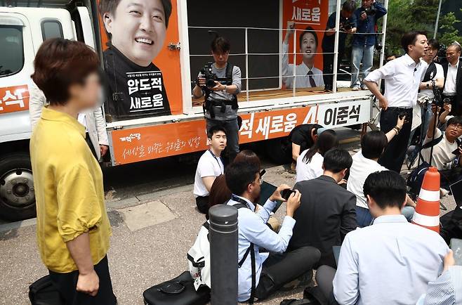 이준석 개혁신당 대통령 후보가 28일 서울 영등포구 여의도공원에서 유세를 마치고 취재진 질의에 답변하고 있는 가운데 한 시민이 이 후보가 전날 토론회에서 여성 신체를 묘사하며 젓가락 발언을 한 것에 대해 항의하고 있다. 2025.5.28/뉴스1