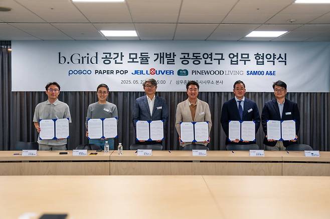 지난 27일, 서울 강동 삼우종합건축사 사무소 본사에서 진행된 'bGrid 공간모듈 개발 공동연구 업무협약식'에 참석한 (왼쪽부터) 고지훈 파인우드리빙 대표, 박대희 페이퍼팝 대표, 송연균 포스코 소장, 손창규 삼우종합건축사사무소 대표, 송권용 제일루버 이사. 김남석 이해라이프스타일 대표가 기념 촬영을 하고 있다. 삼우 제공
