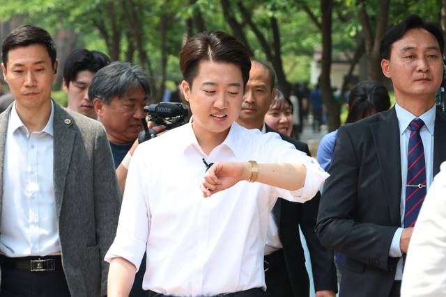 이준석 개혁신당 대선 후보가 28일 서울 여의도공원 유세에서 직장인들에게 인사하던 중 손목시계를 바라보고 있다. 이 후보는 전날 TV토론에서 여성 신체를 지칭한 원색적 발언에 대해 사과했다. 연합뉴스