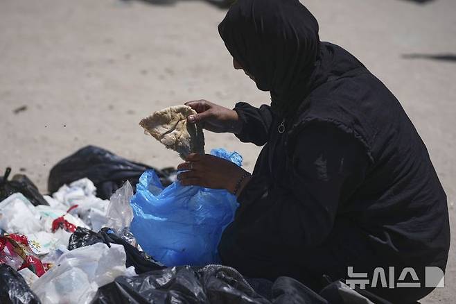[가자시티=AP/뉴시스] 가자지구 내 팔레스타인 주민들의 절박함이 커지는 가운데 지난 25일(현지 시간) 다섯 자녀를 둔 40세 여성 이슬람 아부 타에마가 가자시티 쓰레기 더미 속에서 빵 한 조각을 줍고 있다. 2025.05.27.