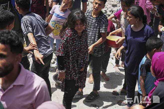 [자발리아=AP/뉴시스] 19일(현지 시간) 가자지구 북부 자발리아의 급식소에 구호 음식을 받으려는 팔레스타인 주민들이 몰려들고 있다. 이스라엘은 지난 10주간 가자지구 내 구호물자 반입을 전면 차단해 왔던 봉쇄를 완화하고 기본 식량 반입을 허용하기로 했다. 2025.05.20.