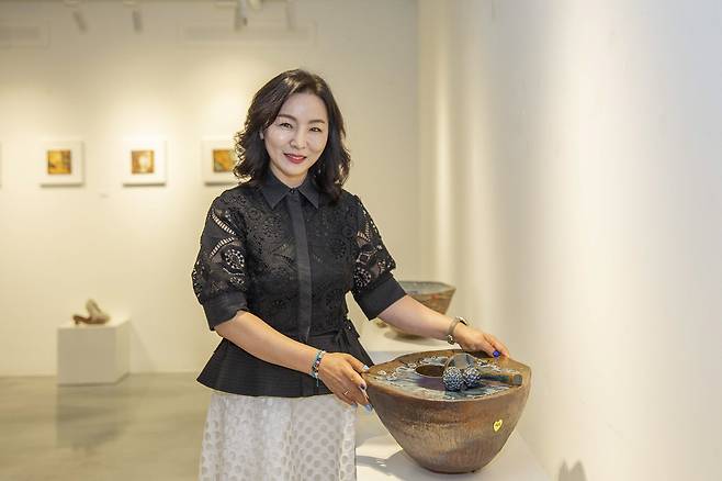 20년 만에 첫 개인전을 연 도예가 진해주 작가가 ‘골프장 그린’을 형상화한 자신의 작품 앞에서 포즈를 취하고 있다. /칠곡군 제공