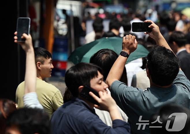 제21대 대통령선거 사전투표 첫 날인 29일 서울 중구 소공동주민센터에 마련된 투표소에서 직장인들이 점심시간 투표를 위해 대기하며 길게 늘어선 투표 인파를 스마트폰에 담고 있다. 2025.5.29/뉴스1 ⓒ News1 오대일 기자