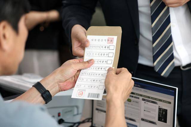 제21대 대통령 사전투표 첫날인 29일 광주 동구 서남동 사전투표소에서 선거사무원이 유권자에게 투표 용지를 건네고 있다. 뉴스1