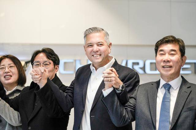 헥터 비자레알(왼쪽 세 번째) 한국GM 사장이 지난 3월 쉐보레 신촌 대리점을 방문해 직원들과 손을 잡고 기념 촬영을 하고 있다. 한국GM 제공