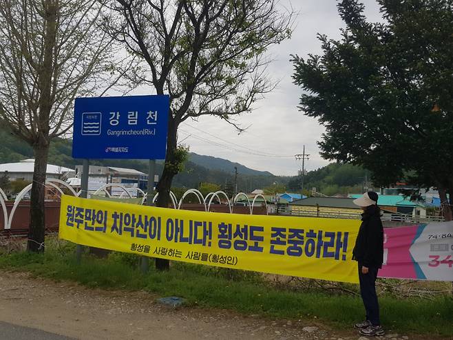지난 25일 강원 횡성군 강림면의 한 주민이 강림천 변에 설치된 현수막을 살펴보고 있다. 강림면 주민들은 원주시 소초면이 지역명칭을 ‘치악산면’으로 변경하려는 데 항의해 이 현수막을 게재했다.