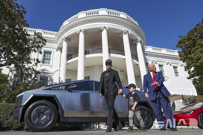 [워싱턴=AP/뉴시스] 도널드 트럼프 미국 대통령과 일론 머스크 테슬라 최고경영자가 11일(현지 시간) 테슬라 사이버트럭을 보며 기자들과 얘기하고 있다. 트럼프 대통령은 “내가 테슬라 차량을 구매하는 이유는 이 차가 훌륭하기 때문이고, 머스크가 이 일에 자신의 에너지와 인생을 바쳤기 때문”이라고 말했다. 2025.03.12.
