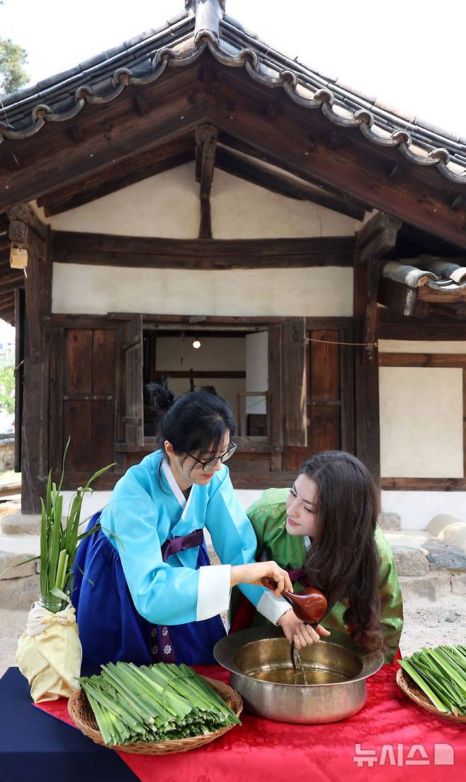 [서울=뉴시스] 김선웅 기자 = 단오(음력 5월 5일)를 이틀 앞둔 29일 서울 종로구 국립민속박물관 오촌댁 앞마당에서 열린 단오 세시행사에서 외국인 관광객이 창포물 머리감기 체험을 하고 있다. 2025.05.29. mangusta@newsis.com