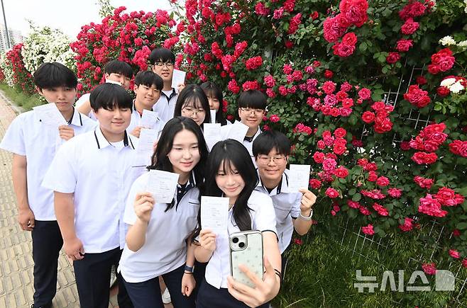 [수원=뉴시스] 김종택기자 = 제21대 대통령선거 사전투표 첫날인 29일 경기 수원시 연무동 행정복지센터에 마련된 사전투표소에서 삼일공업고등학교 3학년 학생 유권자들이 생애 첫 투표를 마친 뒤 장미꽃 앞에서 인증샷을 남기고 있다. 2025.05.29. jtk@newsis.com