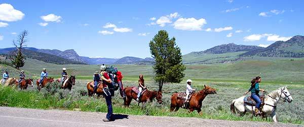옐로스톤의 탐방객들. 커다란 배낭을 짊어진 여행자 옆으로 말을 탄 탐방객들이 지나가고 있다. 옐로스톤국립공원에는 92개소의 탐방로 출입구, 1,609km에 달하는 탐방로hiking trail, 24km의 데크 탐방로boardwalk가 있다.