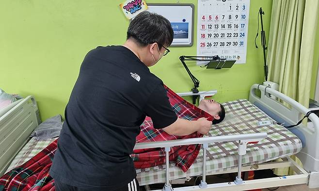 경기도의 한 장애인거주시설에서 생활지도원이 침대에 누워 있는 장애인을 위해 이불을 덮어주고 있다. 장한서 기자