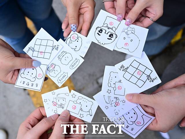사전투표를 마친 시민들이 도장을 찍은 캐릭터 그림을 들고 기념촬영하고 있다. MZ세대(밀레니얼+Z세대)를 중심으로 연예인·캐릭터 등을 활용한 '맞춤형 투표 인증 용지'가 유행이다.