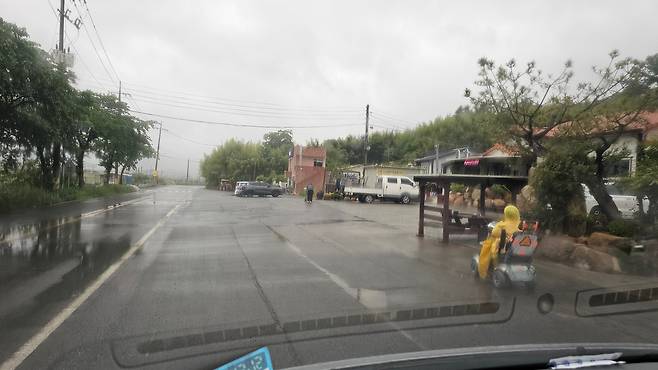 지난 23일 오전 비가 내리는 날 노란 우비를 입고 전동차를 끌며 마을 회관으로 향하는 오무식 할머니의 모습. /오세웅 마을이장 제공