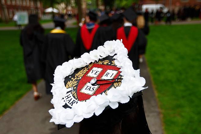29일(현지 시각) 미국 매사추세츠주 케임브리지 하버드대학교에서 열린 제374회 졸업식 시작에 앞서 한 졸업생이 유학생들을 응원하는 의미로 하얀 꽃을 사각모에 꽂고 있다. /EPA 연합뉴스