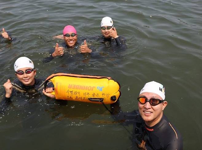 오세훈 서울시장(오른쪽 아래)이 30일 '쉬엄쉬엄 한강 3종 축제' 1일차 수영종목에 출발 전 '수영하기 너무 좋은 한강으로 오세요 수질 환상적!'이라고 직접 쓴 안전부이를 들고 도강을 준비하고 있다.ⓒ서울시 제공