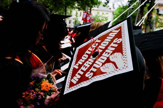 미국 매사추세츠주 케임브리지에 위치한 하버드 374회 졸업식이 29일(현지시각) 열린 가운데 한 졸업생이 학사모에 ‘외국 학생들을 보호하라’고 쓰인 손팻말을 붙이고 있다. 사진 로이터 연합뉴스