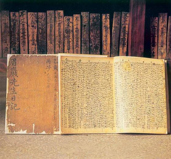 유희춘이 말년에 기록한 『미암일기』. 배경은 그의 전집 『미암집』의 목판들이다. [사진 지역N문화, 국가유산포털]