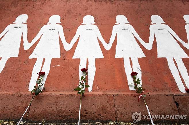 여성 살해 피해자들을 상징하는 흰색 실루엣 벽화에 놓인 꽃들 [EPA 연합뉴스 자료사진. 재판매 및 DB 금지]