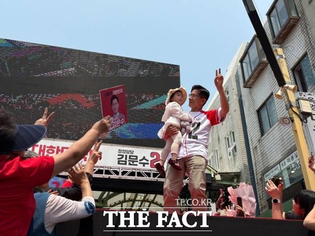 김문수 국민의힘 대선 후보가 31일 속초 관광수산시장 유세 현장에서 아이를 안고 지지자들을 향해 인사하고 있다. /속초=김수민 기자