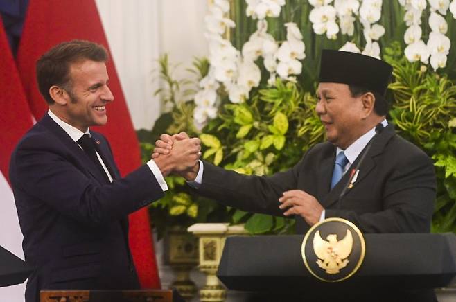 에마뉘엘 마크롱(왼쪽) 프랑스 대통령이 28일(현지시간) 인도네시아 자카르타 메르데카 궁에서 프라보워 수비안토 인도네시아 대통령과 악수하고 있다. 마크롱 대통령은 30일 싱가포르 샹그릴라 안보대화에서 미국과 중국의 편가르기에 맞서 유럽과 아시아가 공조하자고 제안했다. 신화 연합