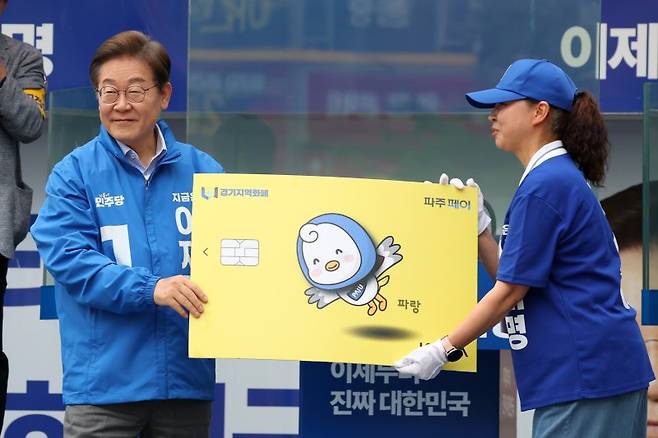 이재명 더불어민주당 대선후보가 지난 20일 경기 파주시 금릉역 중앙광장에서 열린 유세에서 선거운동원으로부터 경기지역화폐 파주페이 모형을 받고 있다. /사진=뉴시스화상