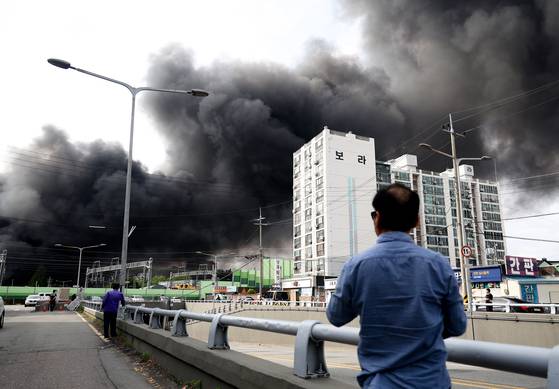 지난 17일 오후 광주 광산구 송정동 금호타이어 광주공장에서 연기가 나오는 가운데 한 시민이 이를 지켜보고 있다. 연합뉴스