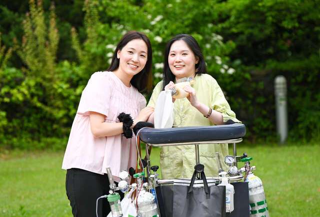 김온유(오른쪽) 작가가 최근 서울 강남구 한 종합병원 내 산책로에서 앰부(수동식 인공호흡기)를 잡은 채 동생 김주영씨와 함께 활짝 웃고 있다. 신석현 포토그래퍼
