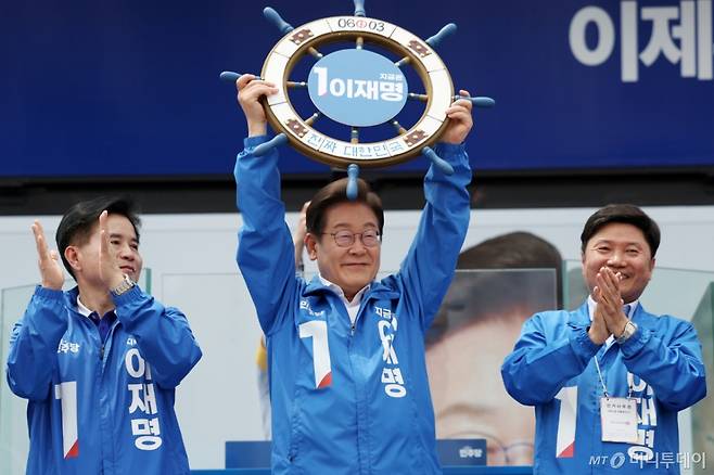 [평택=뉴시스] 조성우 기자 = 이재명 더불어민주당 대선후보가 31일 오후 경기 평택시 배다리생태공원에서 열린 유세에서 '진짜 대한민국' 이라고 적힌 조타기를 들어 보이고 있다. 2025.05.31. xconfind@newsis.com /사진=조성우