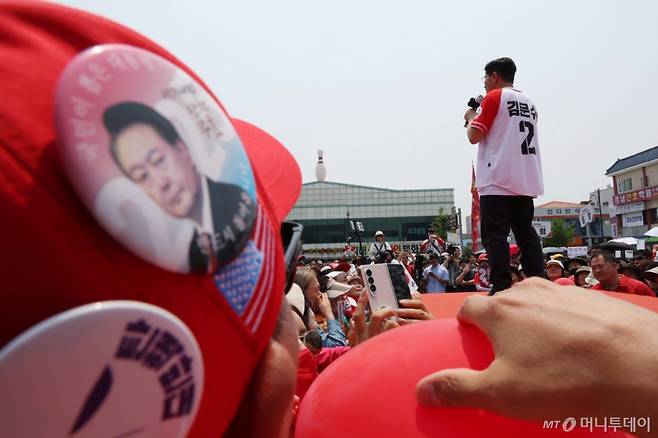 [김해=뉴시스]  김문수 국민의힘 대선 후보가 28일 경남 김해수로왕릉 공원에서 유세를 하고 있다. 어느 윤석열 전 대통령 지지자가 이를 가까이서 지켜보고 있다. 2025.05.28 /사진=고승민
