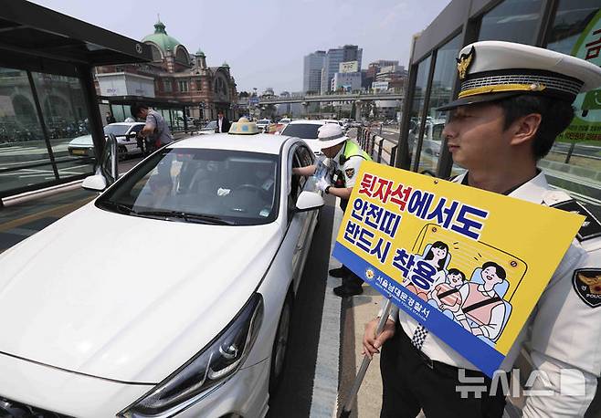 [서울=뉴시스] 김근수 기자 = 27일 서울 중구 서울역 택시승강장에서 서울경찰청 소속 경찰관들이 택시 운전사에게 ‘택시 뒷좌석 안전띠’ 착용 일상화 캠페인을 하고 있다. 2025.05.27. ks@newsis.com