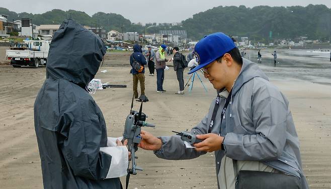 31일 일본 카나가와현 가마쿠라시 에노시마섬 일원 자이모쿠자 해변에서 열린 '2025 세계드론낚시대회 in Japan'에서 참가자들이 강풍으로 망가진 드론을 수리하고 있다.