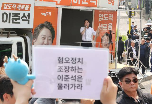 이준석 개혁신당 대선 후보가 30일 서울 동작구 중앙대학교에서 유세 중인 가운데 일부 학생들이 최근 이 후보의 TV토론 여성 신체 관련 발언을 규탄하며 팻말을 들고 있다. 연합뉴스