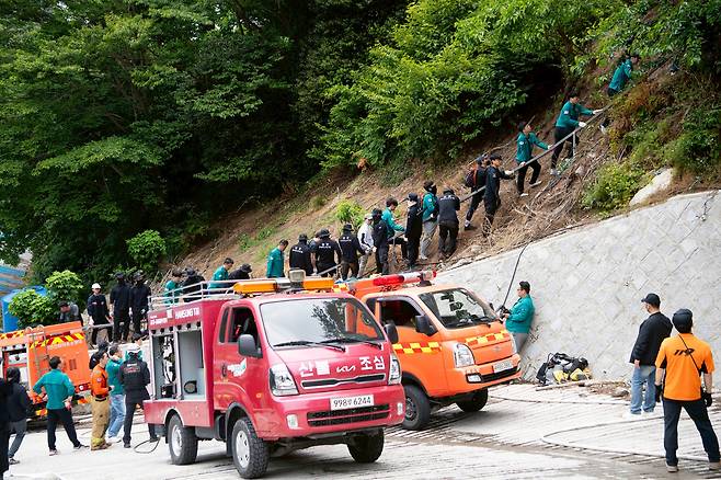화재 현장으로 접근하기 위해 모노레일을 잡고 올라가는 울릉군청 공무원과 경찰관. /울릉군