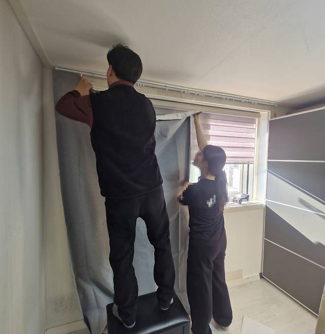 보호관찰 대상자 자녀의 학업 환경을 위해 커튼을 달아주고 있다.(도봉구 제공)