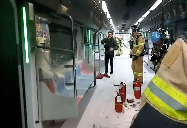 Firefighters check for remaining flames and assess the situation inside a Seoul Metro Line 5 subway car shortly after an arson attack on the morning of May 31, 2025. Fire extinguishing agents cover the floor, and several fire extinguishers are seen nearby./Yeongdeungpo Fire Station