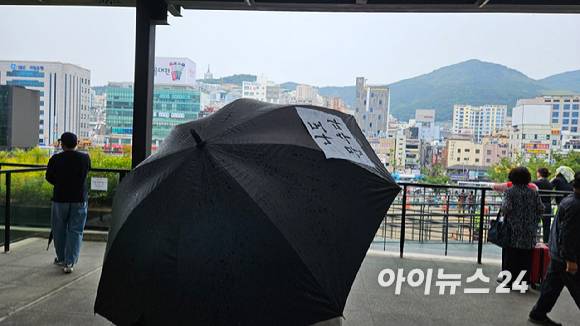 2일 부산역 광장에서 열린 국민의힘 김문수 대선 후보 부산 총괄 거점 유세에서 한 시민이 '나도 문수다'가 적힌 문구가 붙은 우산을 들고 빗속에서 유세 현장을 지켜보고 있다. [사진=김보선 기자]