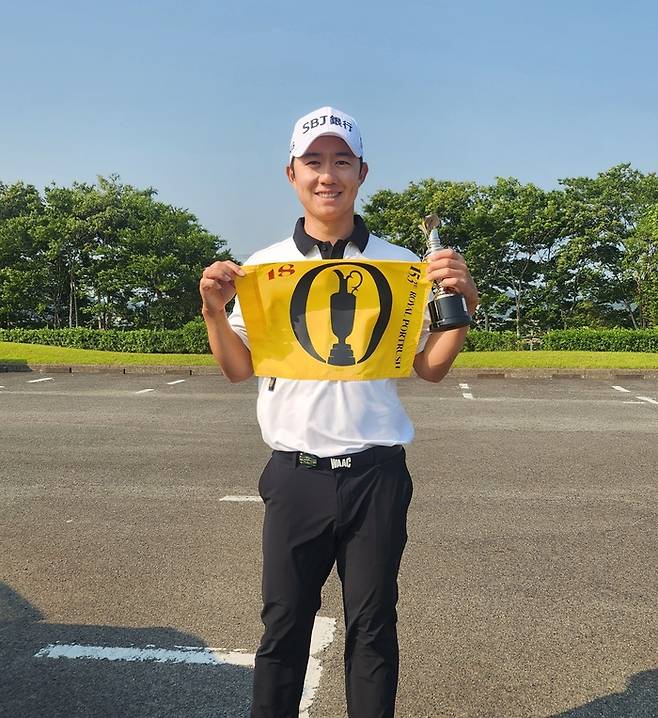 송영한이 제153회 디오픈 깃발을 들고 환하게 웃으며 포즈를 취하고 있다. 송영한