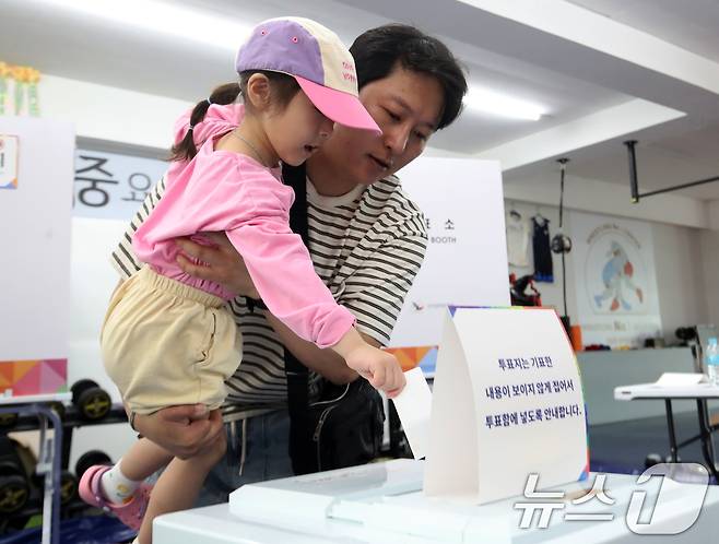 제21대 대통령 선거일인 3일 부산 수영구 레슬링넘버원 멀티짐에 마련된 남천제2동 제3투표소에서 유권자가 아이와 함께 투표를 하고 있다. 2025.6.3/뉴스1 ⓒ News1 윤일지 기자