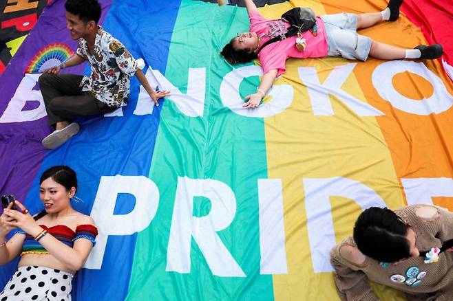 지난 1일(현지시간) 태국 방콕에서 열린 성소수자 행진에 참가한 사람들이 대형 무지개 깃발에서 포즈를 취하고 있다. 로이터 연합뉴스