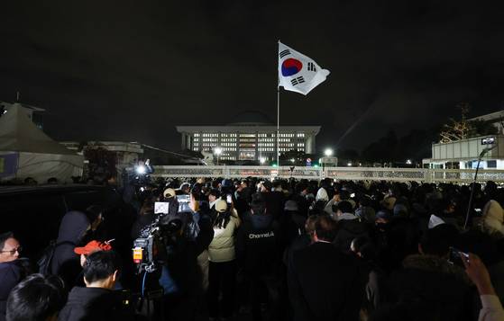 윤석열 전 대통령이 선포한 비상계엄의 해제 요구 결의안이 국회 본회의에서 통과된 지난해 12월 4일 새벽 서울 영등포구 국회 정문 앞에 모여든 시민들이 자리를 지키고 있다. 뉴시스