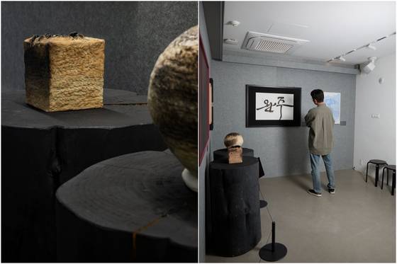 Ceramics by artist Jeong Ha-hyeon, left, and actor Park Jeong-min looks at works by calligrapher Kim So-young at the ″Wanju:Record:01″ exhibition at the LCDC Seoul in Seongdong District, eastern Seoul [LCDC SEOUL]